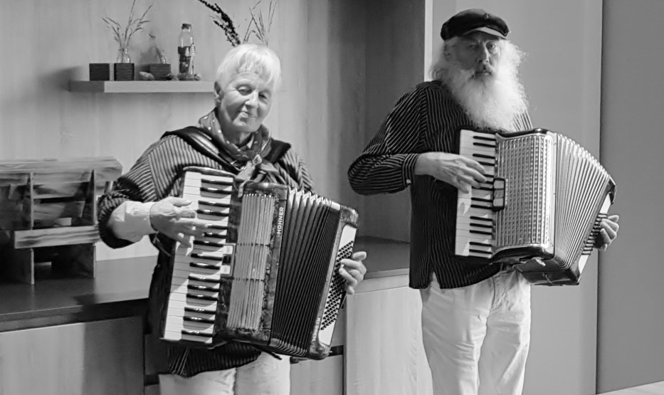 ältere Frau und Mann mit langem Bart spielen Akkordeon