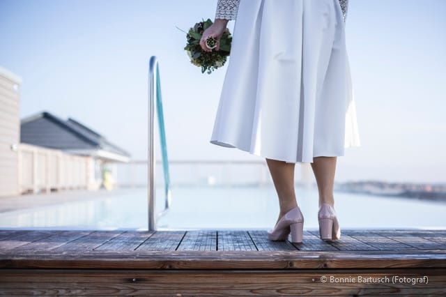 Braut mit Blumenstrauß vor dem Pool der Sandburg