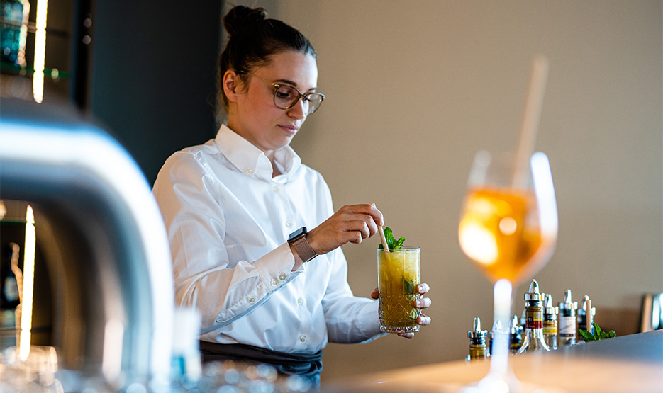 Frau mit Brille mischt einen Cocktail